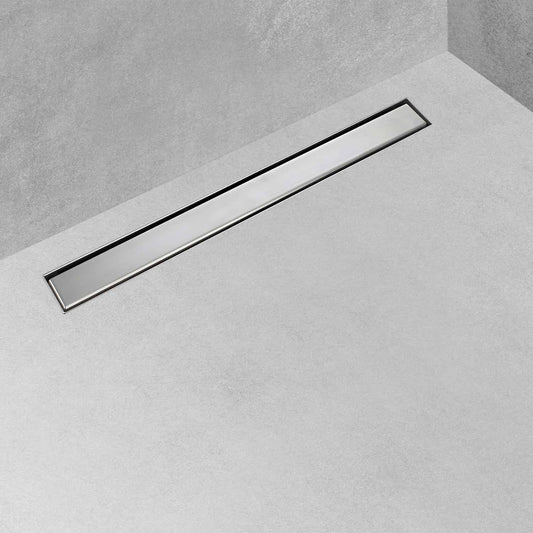 Calha de duche com grelha plana instalada num pavimento de casa de banho em microcimento cinza.