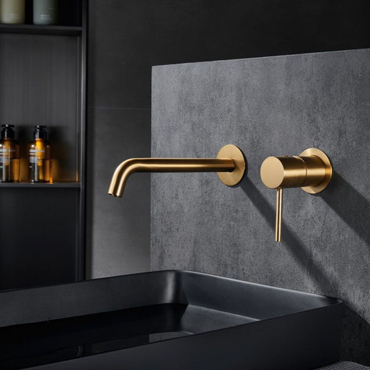 Torneira de lavatório encastrada Monza Ouro Mate instalada em parede escura, sobre lavatório preto