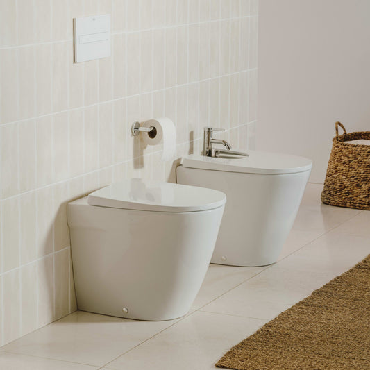 Ambiente de casa de banho minimalista com conjunto de sanita e bidé de pousar Ona da Roca em branco.