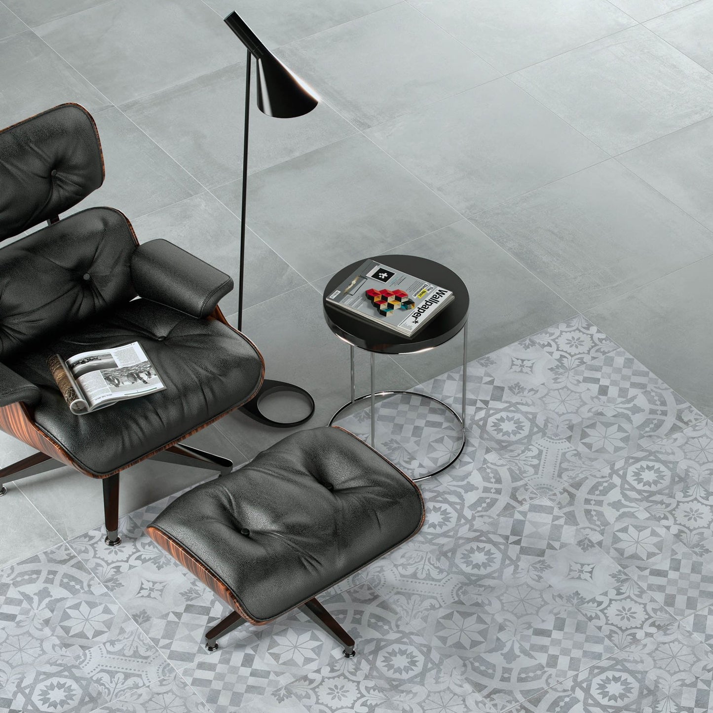 Ambiente de sala de estar moderna com o pavimento cinza Newstreet Fog Eco e uma secção de pavimento decorado da mesma coleção, junto a uma poltrona preta.