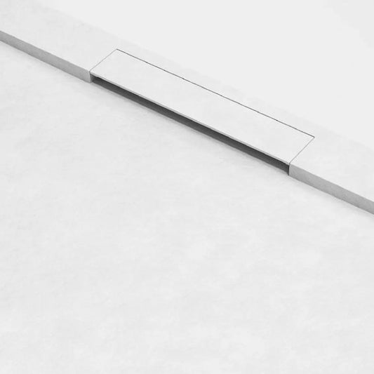 alt='Pormenor da grelha de escoamento linear e da textura de pedra da base de duche New Ekostone branca.'