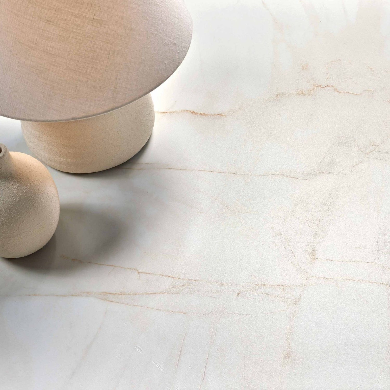 Vista de topo do pavimento cerâmico Marble Dolomita Blanco Polido, com um candeeiro e uma jarra decorativa a ilustrar a superfície polida.