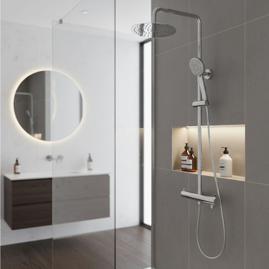 Coluna de duche VEGA PLUS round cromada instalada numa casa de banho moderna com paredes cinzentas e espelho retroiluminado.