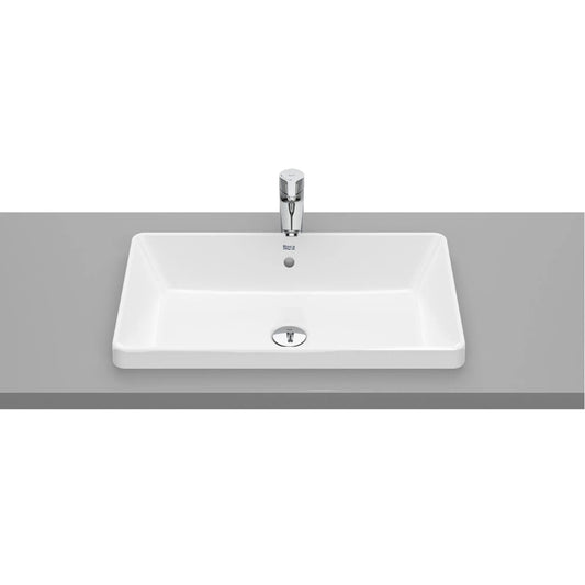 alt='Lavatório de encastrar The Gap da Roca, instalado numa bancada cinzenta com uma torneira cromada.'