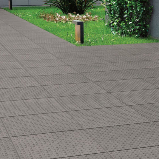 Pavimento cerâmico Berice Top Dark Grey 33x33cm aplicado num caminho exterior junto ao relvado   