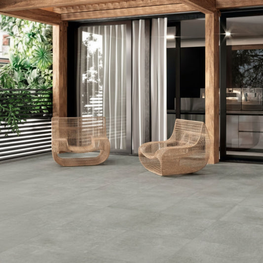 Pavimento cerâmico Eaton Ash 45x45cm aplicado em zona de lazer exterior com poltronas de design.