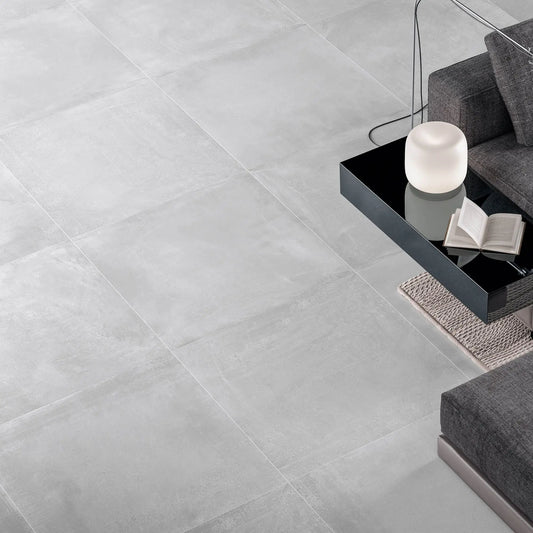 alt='Pavimento de efeito cimento cinza Newstreet Fog aplicado no chão de uma sala de estar moderna.'