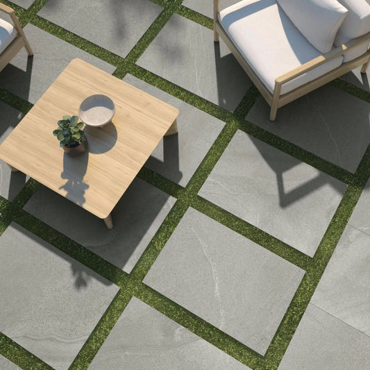 alt='Lajes de pavimento Pamesa Burlingstone Gris de 20mm instaladas como caminho sobre um relvado num jardim.'