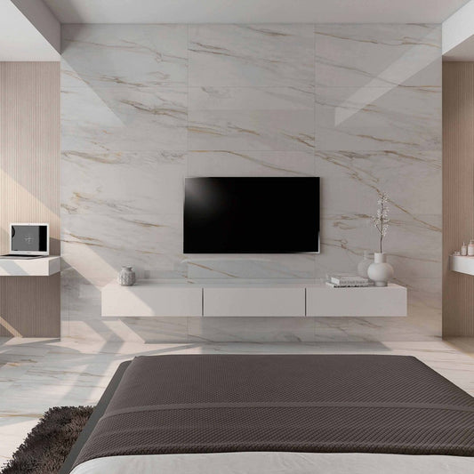 alt='Parede de sala moderna revestida com porcelânico Roca Calacatta Gold, criando um painel de destaque para a televisão.'