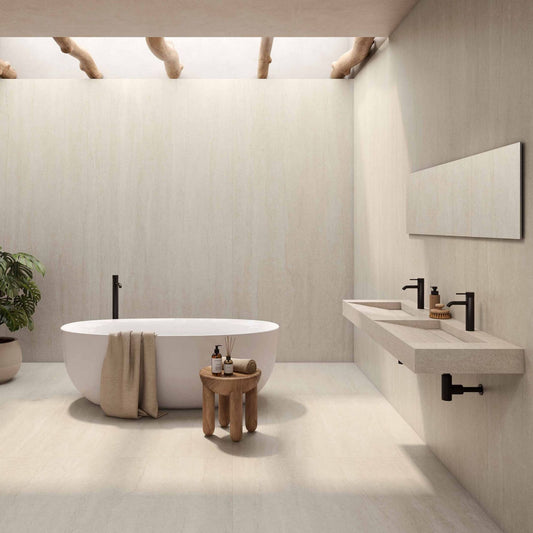 Alt Text= 'Casa de banho luxuosa com o cerâmico Serena Veincut Bone aplicado no pavimento e nas paredes, com uma banheira oval branca.'