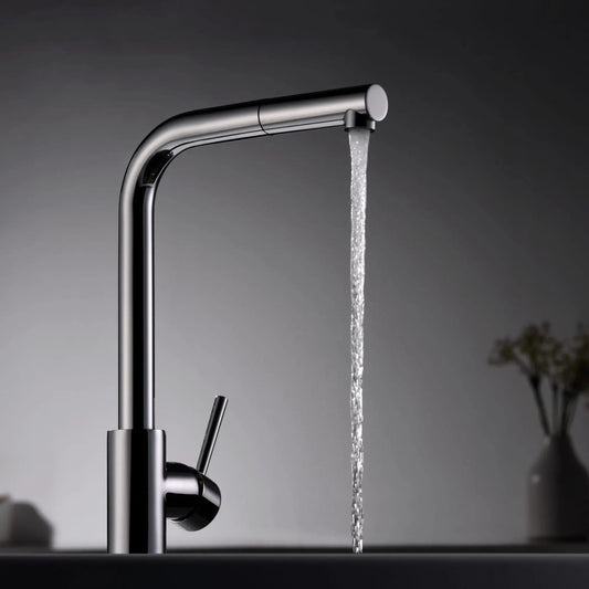 alt='Vista de perfil da torneira de cozinha Imex Malta cromada com um jato de água a correr, num ambiente de cozinha moderno.'