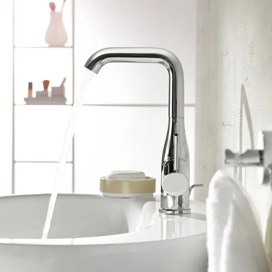 Torneira Grohe Essence New L cromada bica alta instalada em lavatório, a debitar água com fluxo EcoJoy.